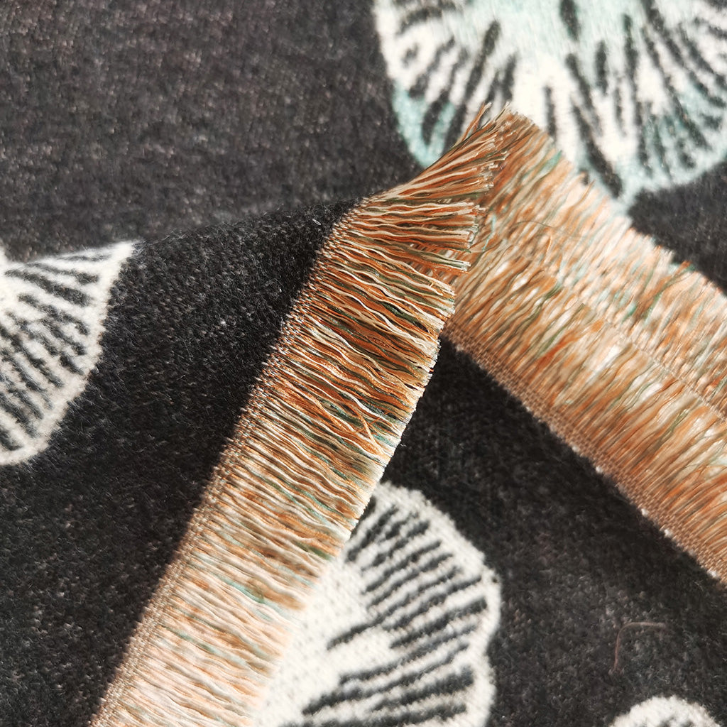Close-up detail of the fringe of a black cashmere-feel women scarf. The fabric detail shows the winter scarf is very soft and warm, and crafted from high-quality workmanship