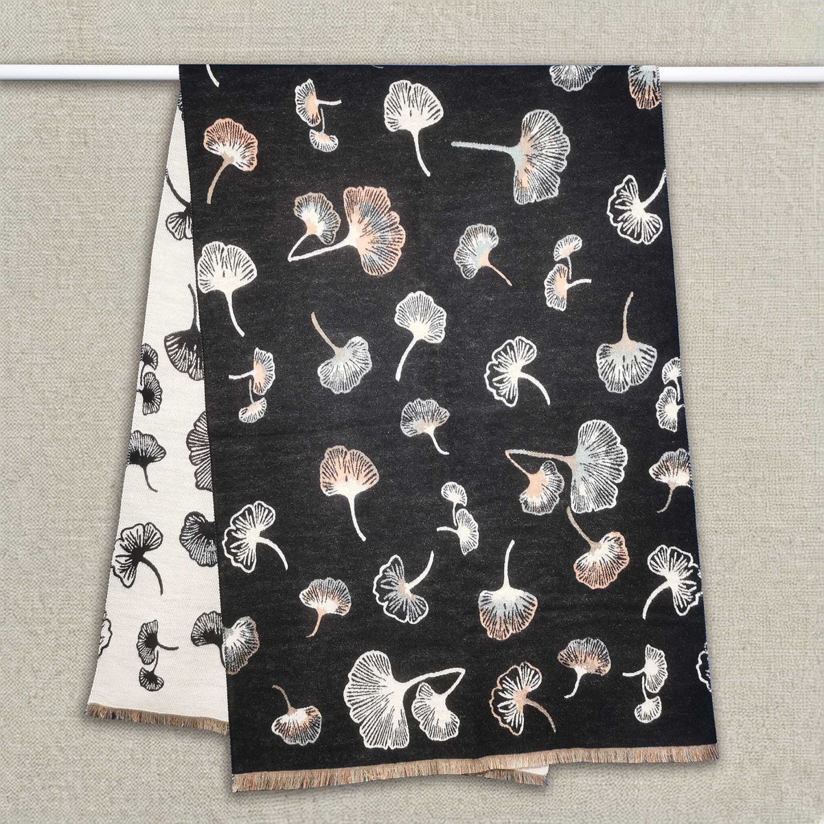 A black women scarf with ginkgo leaf pattern is hanging on clothing rack, The cashmere-feel fabric is very soft, warm and with high-quality workmanship. This fashion scarf is reversible and large size, approx. width 65 cm, length 180 cm and weight 330g