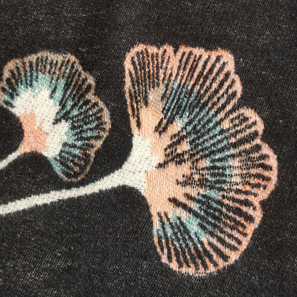Close-up texture detail of a black cashmere-feel women scarf. The clear ginkgo leaf pattern indicate the wrap is made with high-quality workmanship