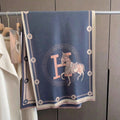 Luxury blue elegant horse print scarf with blush pink letter pattern and ivory border displayed on hanger rack