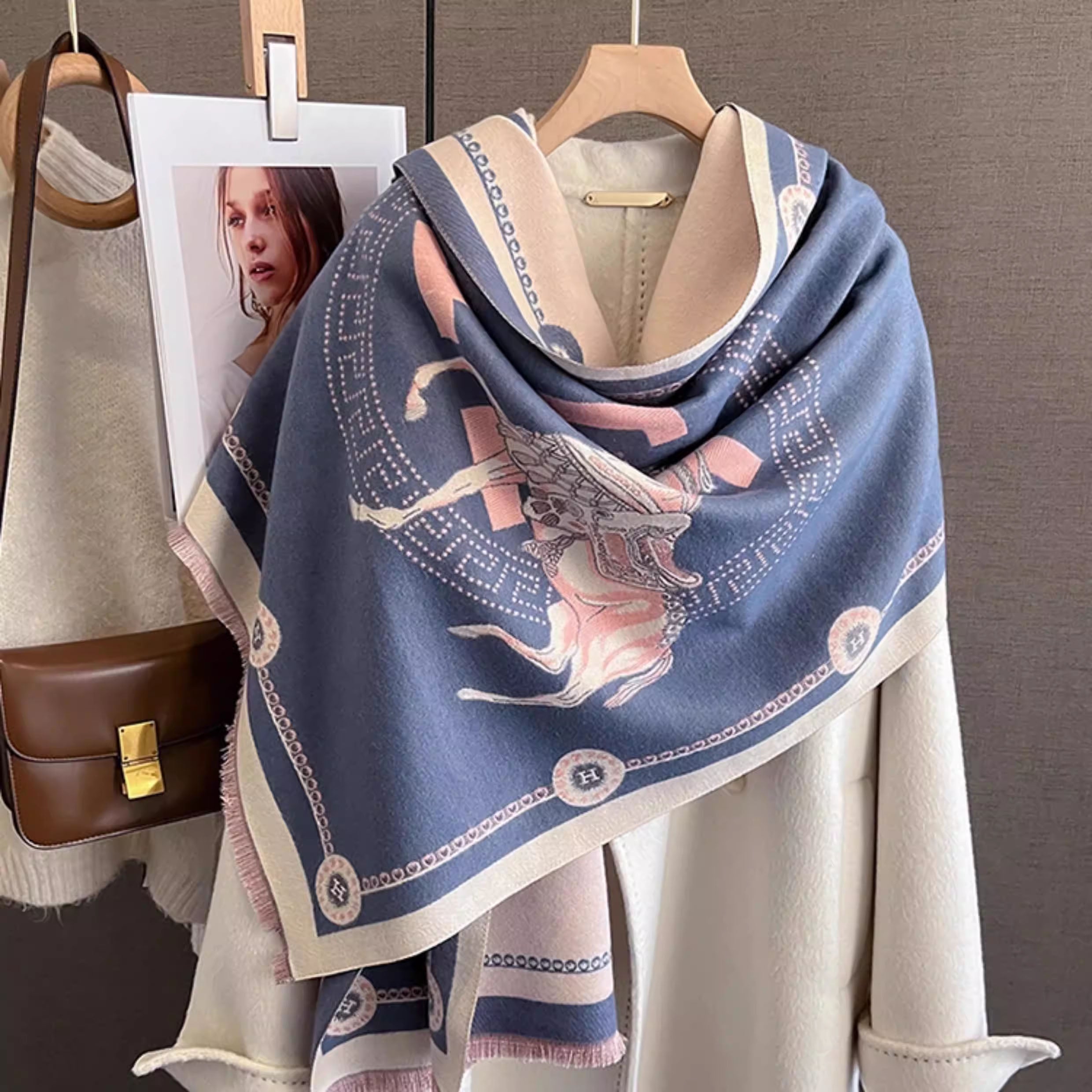 Woman's oversized blue jacquard horse print shawl with ivory border and blush pink fringe draped over white coat 