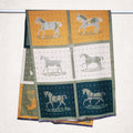 cashmere-feel olive-green winter scarf with mustard yellow and teal panel and horse print. The unisex scarf hanging on rod. Large size, approx. width 65 cm, length 180 cm and weight 330g