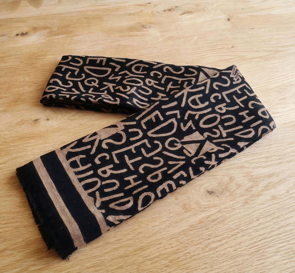 Black and camel letter pattern winter scarf folded on a wooden table as a men’s neck scarf style. This scarf is crafted with cashmere-feel fabric which is soft and warm. Large size, approx. 65 cm width,  180 cm length and 330g