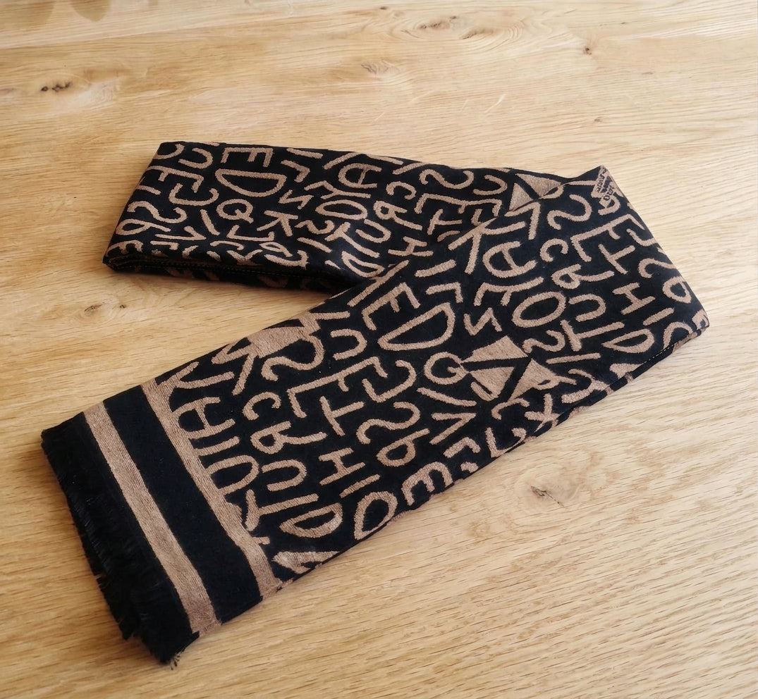 Black and camel letter pattern winter scarf folded on a wooden table as a men’s neck scarf style. This scarf is crafted with cashmere-feel fabric which is soft and warm. Large size, approx. 65 cm width,  180 cm length and 330g