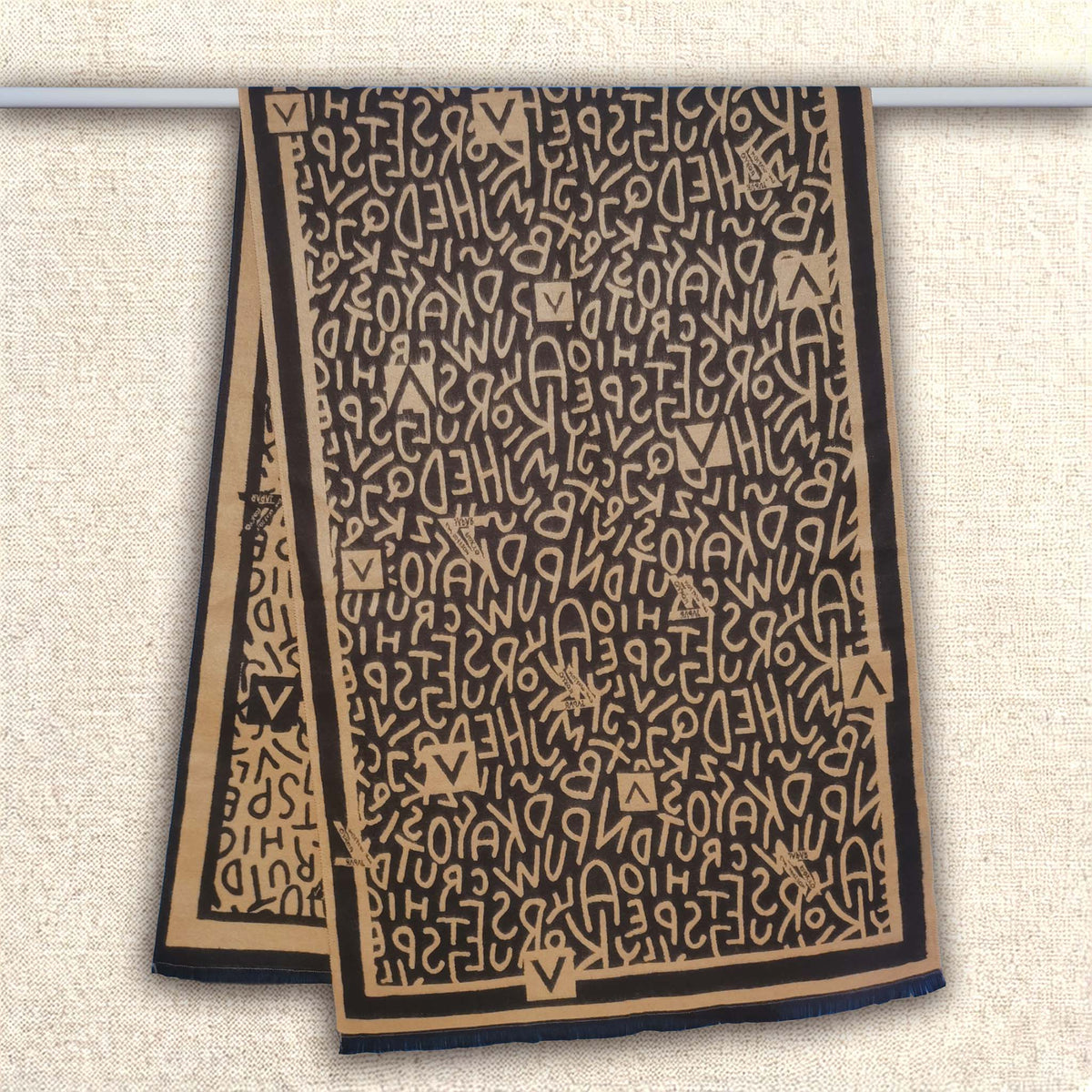Full view of winter scarf hanging on a rod showing black and brown letter pattern design, and high-quality cashmere-feel fabric. Fashion unisex scarf. Large size, approx. 65 cm width,  180 cm length and 330g