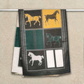 Dark green cashmere-feel winter scarf with yellow and cream panels and horse pattern hanging on clothing rack