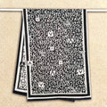 Fashion black and white letter print blanket scarf for women hanging on clothing rack. Showing the full view of the large size cashmere-feel winter scarf