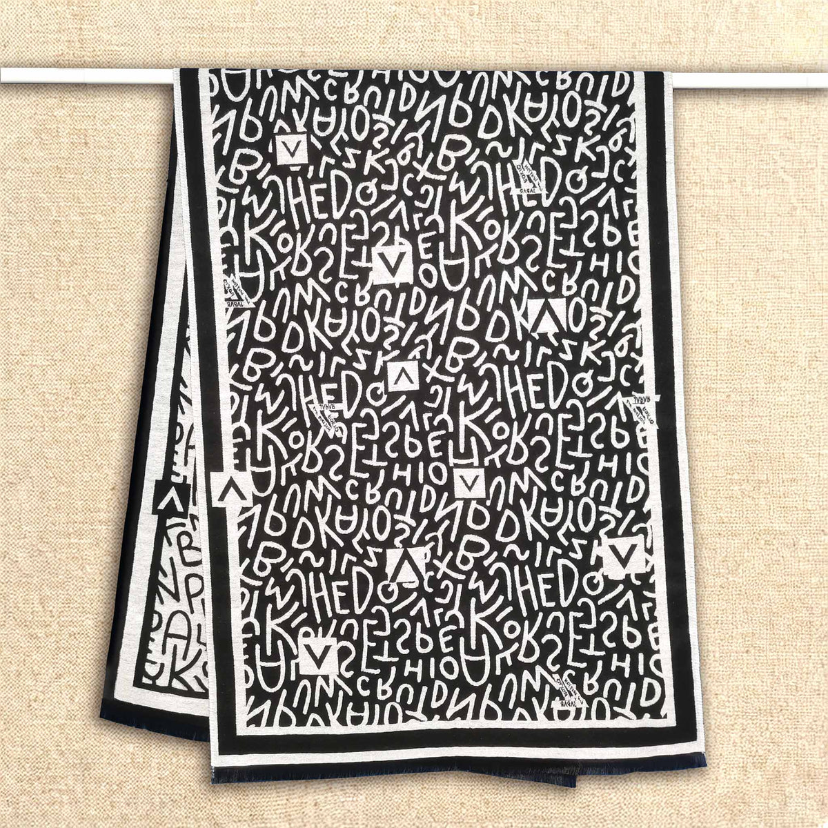 Fashion black and white letter print blanket scarf for women hanging on clothing rack. Showing the full view of the large size cashmere-feel winter scarf