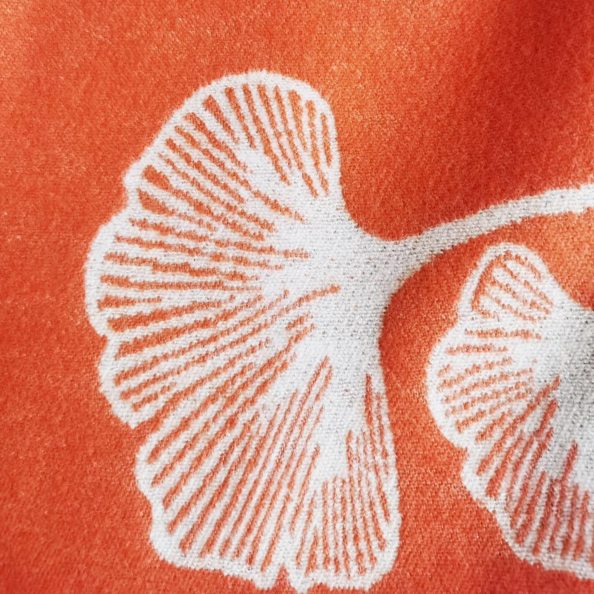 Close-up texture detail of an orange cashmere-feel women scarf. The clear floral pattern indicate the wrap is made with high-quality workmanship