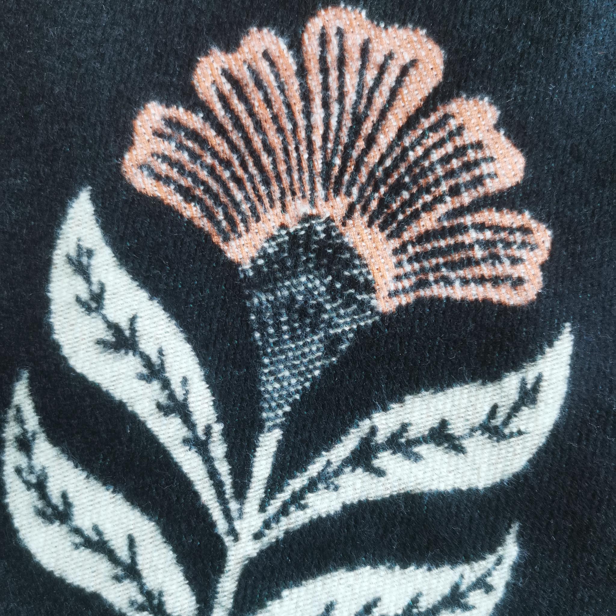 Close-up of cashmere-feel fabric women scarf showing coral flower accents on black background
