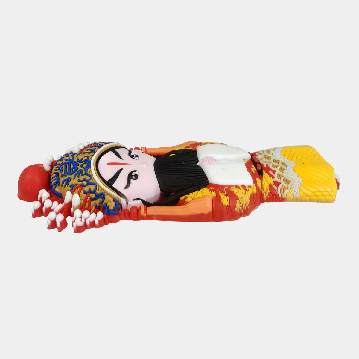 Side view of 3D soft rubber Peking Opera character magnet showing thickness and details. A stylized figurine of a Chinese opera performer in a dramatic pose, wearing a vibrant red and yellow costume with a detailed multicolored headdress, set against a plain light gray background.