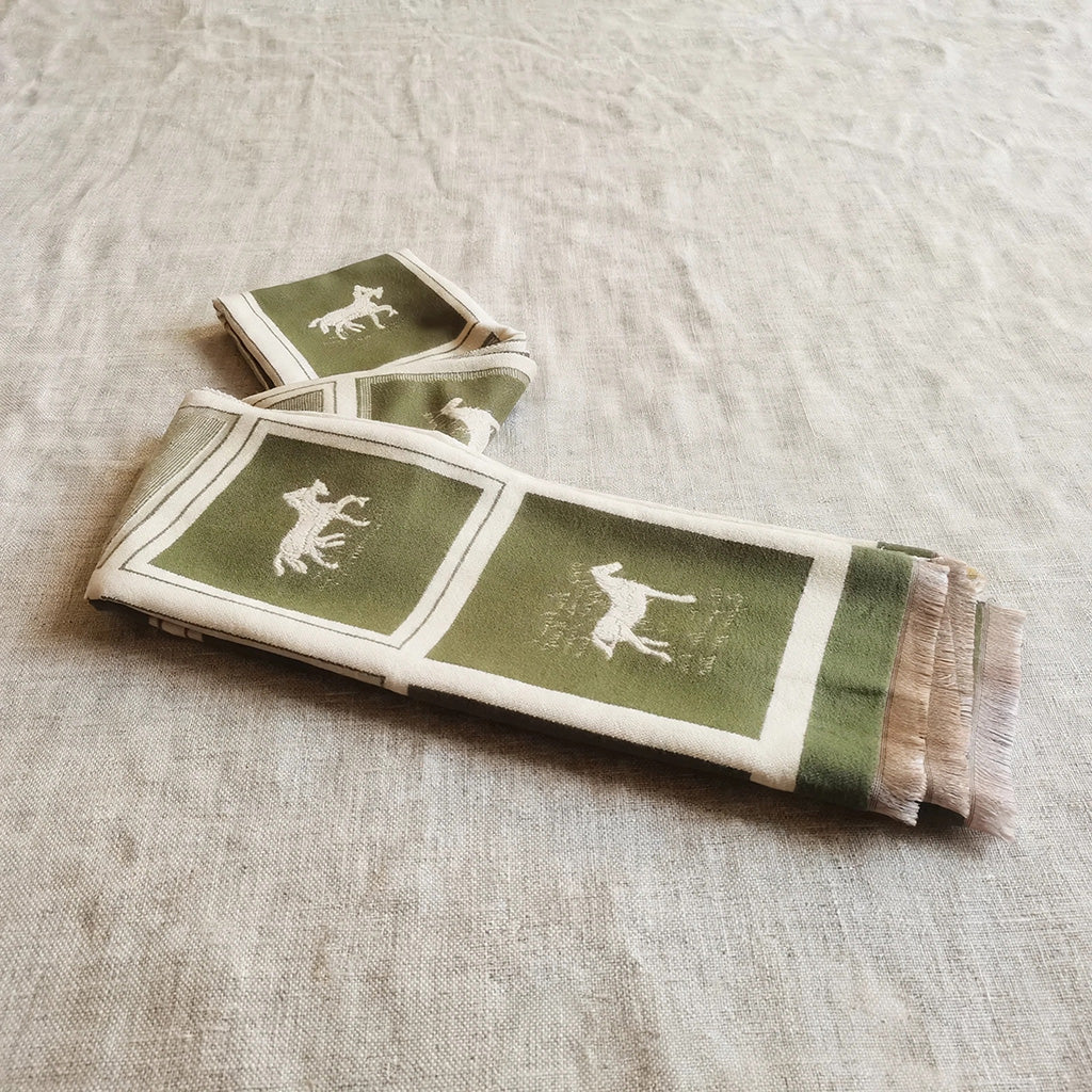 an olive green men scarf with fringe styled on ivory background. This winter scarf is crafted with cashmere-feel fabric in horse pattern and color block design.
