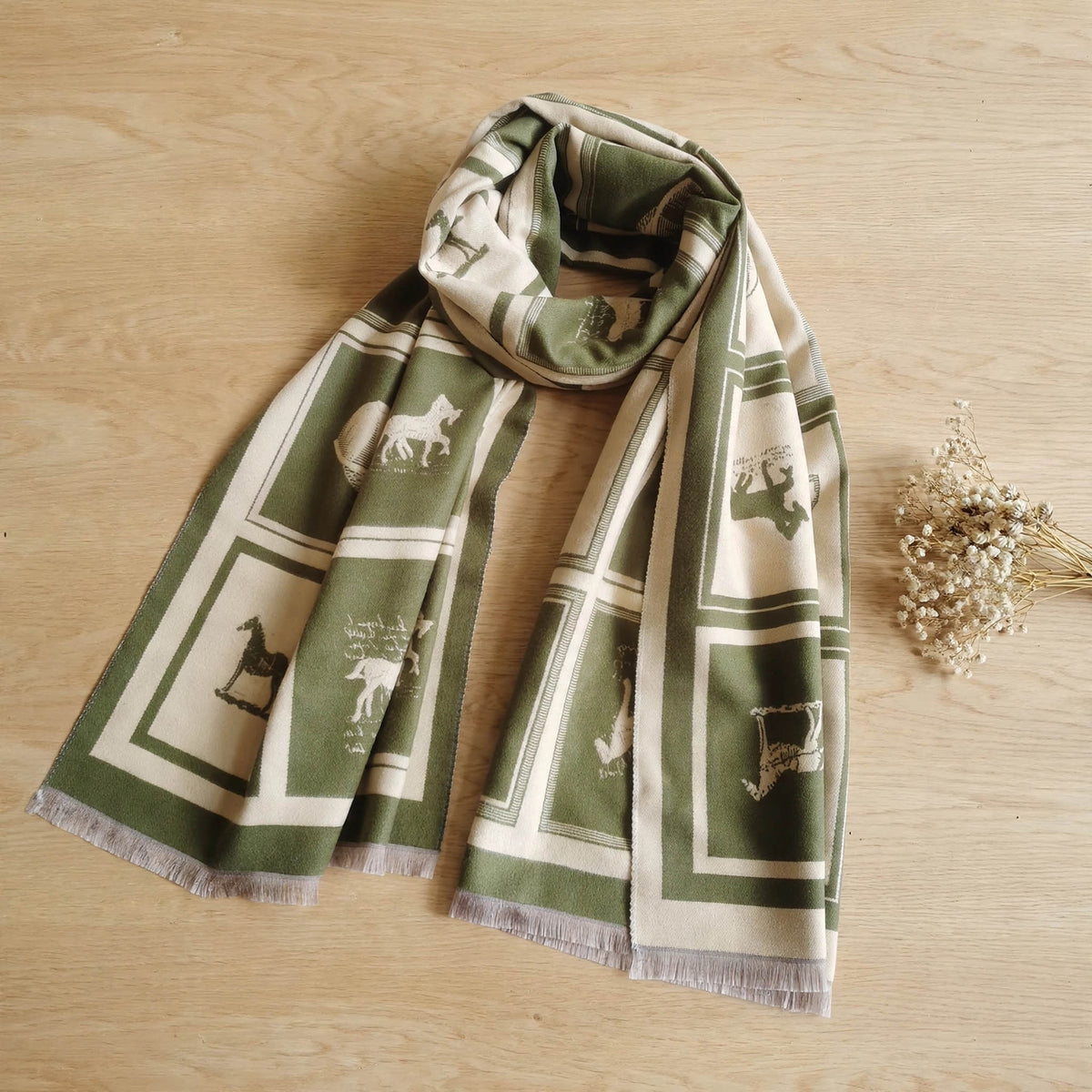 Olive green cashmere-feel large size men scarf styled on light table with a dried flower. This winter scarf is reversible. The clear horse pattern showing the winter men’s neck scarf is very soft, warm and crafted from high-end workmanship