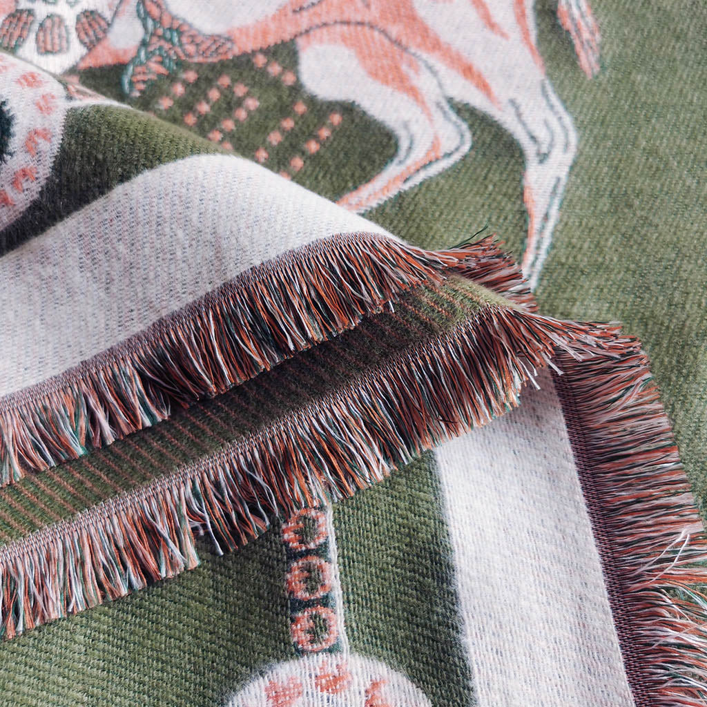 Close-up of oliver green jacquard scarf showing ivory fringe tassel edge and cashmere-feel weave detail