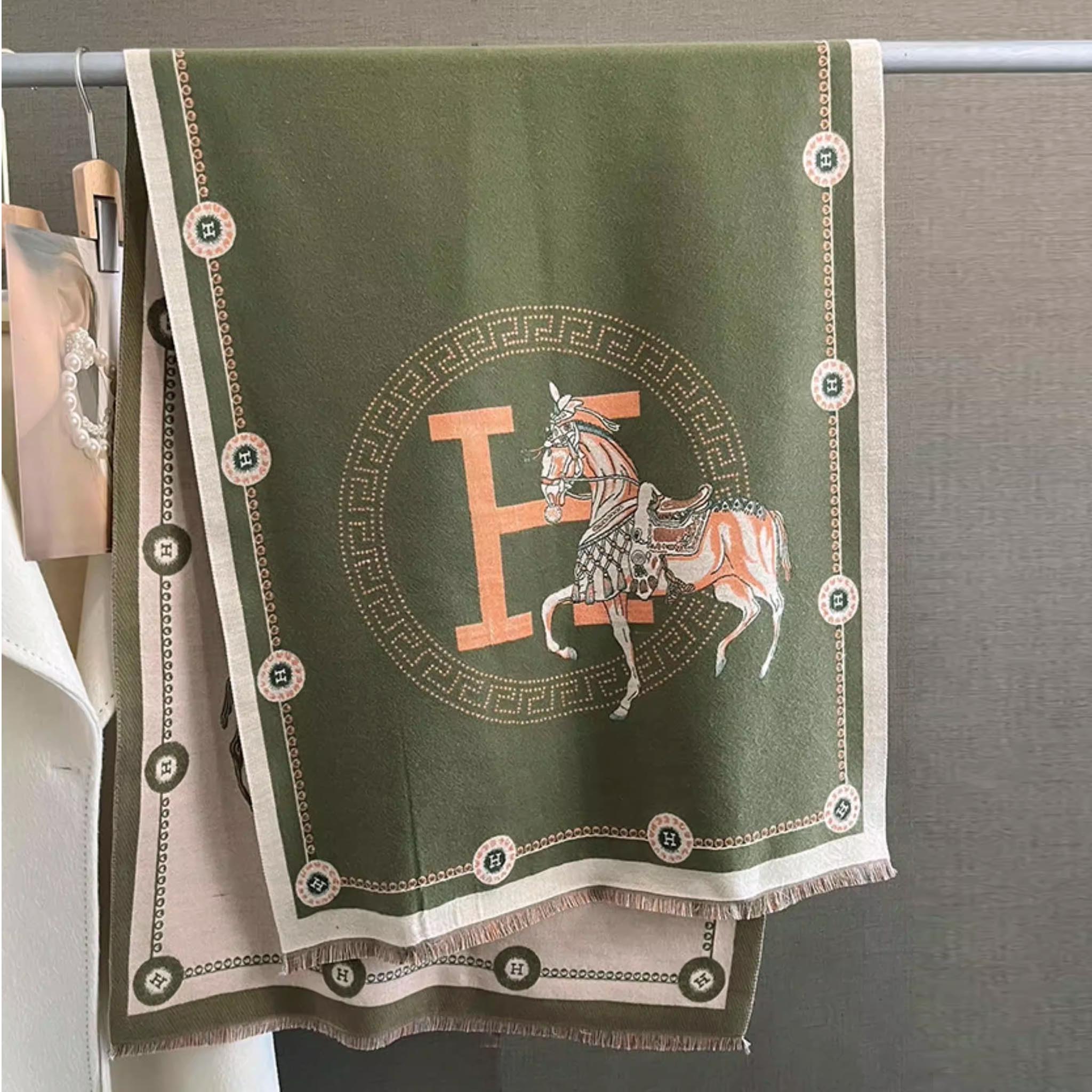 oliver green elegant horse print winter scarf with orange letter and ivory border hanging on display rack