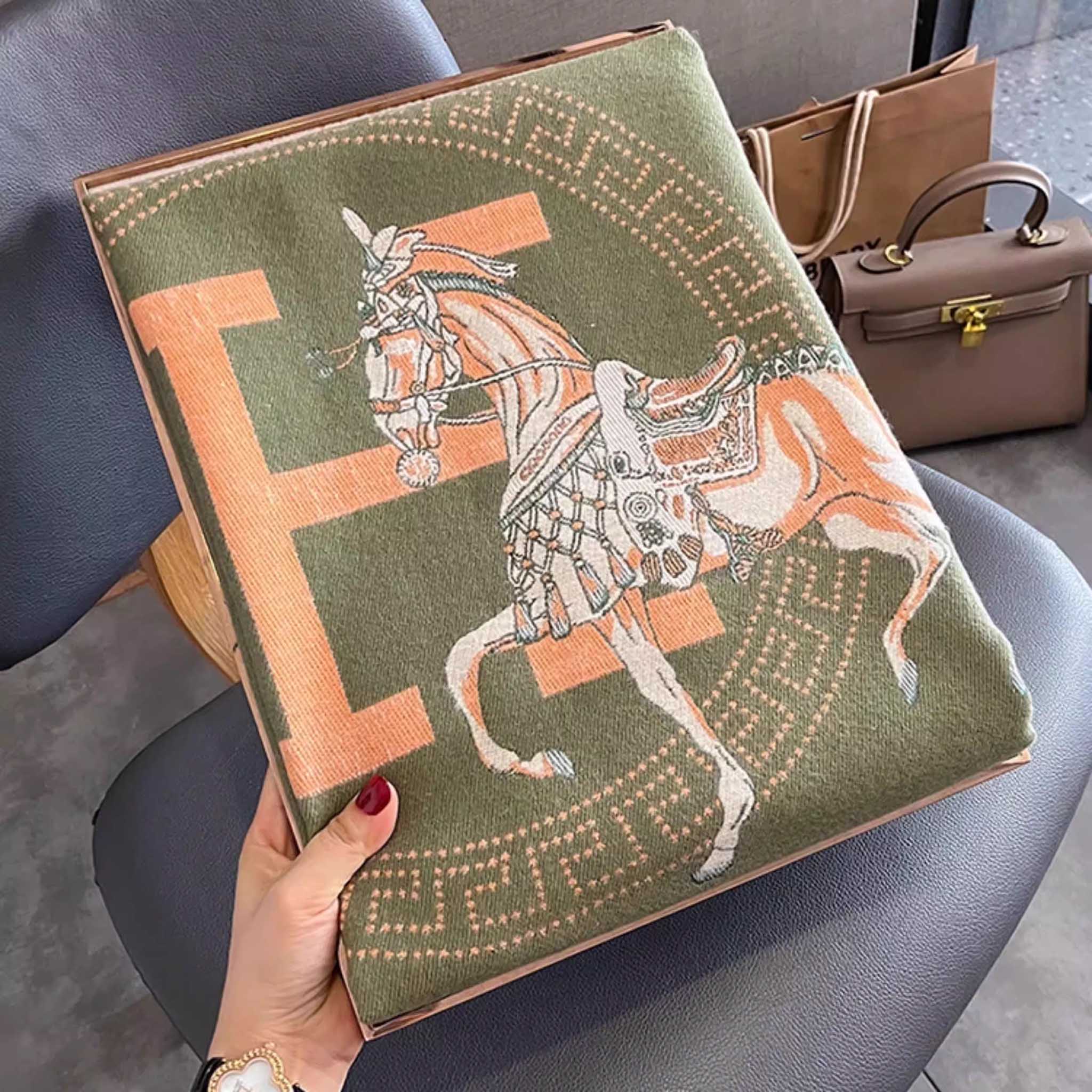 Folded oliver green elegant jacquard horse print scarf with orange letter held in hand