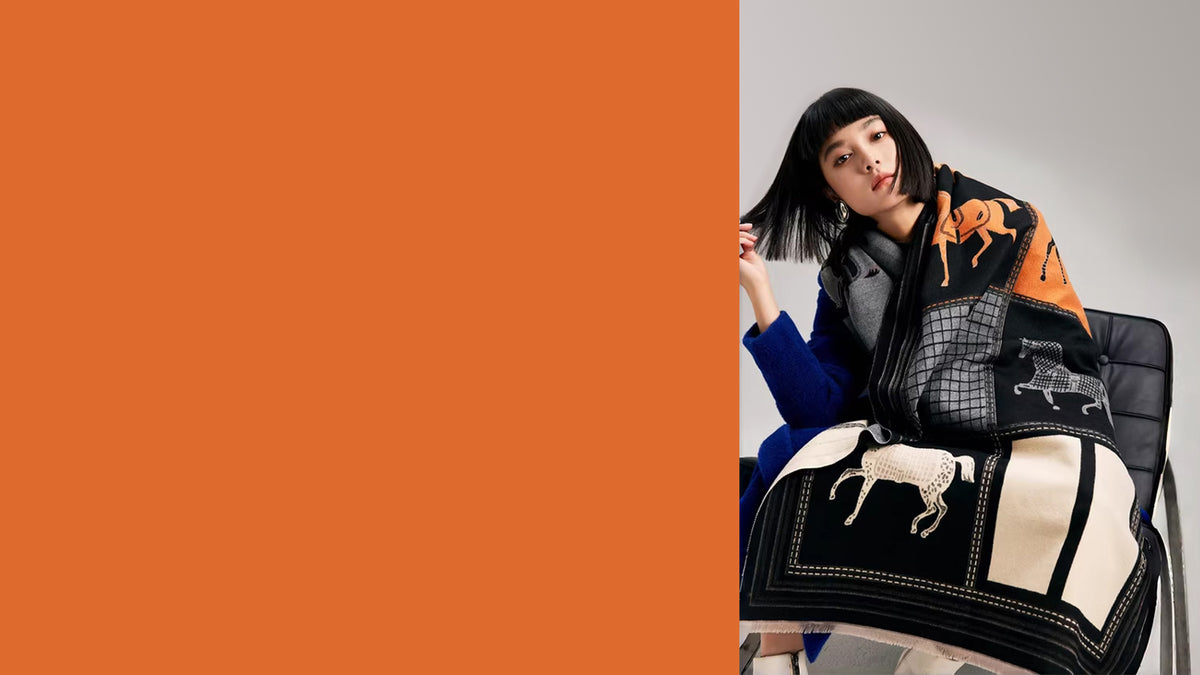 Elegant jacquard women shawl made by cashmere-feel fabric wrapped on a model. The large size scarf shows equestrian horse print in black, white and orange color block.
