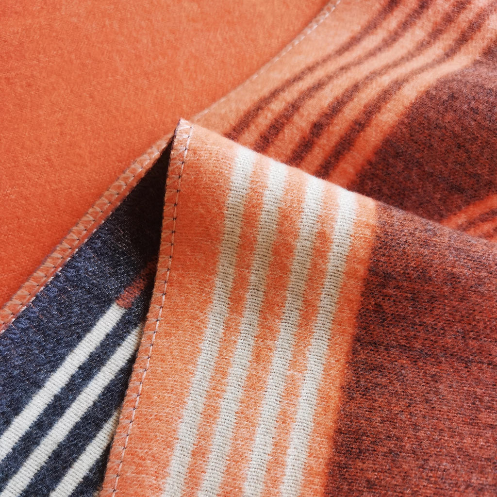 Close-up of luxury orange scarf displaying cashmere-feel fabric detail. It showcases the scarf’s exquisite craftsmanship.