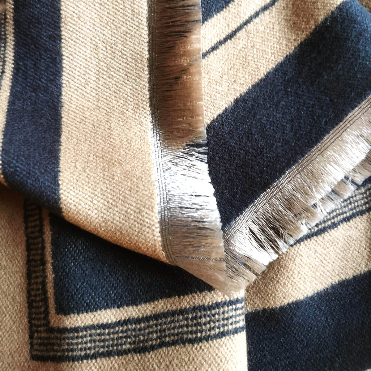 Close-up detail of the fringe of a black camel cashmere-feel men scarf. The fabric detail shows the large scarf is very soft and warm, and crafted from high-quality workmanship
