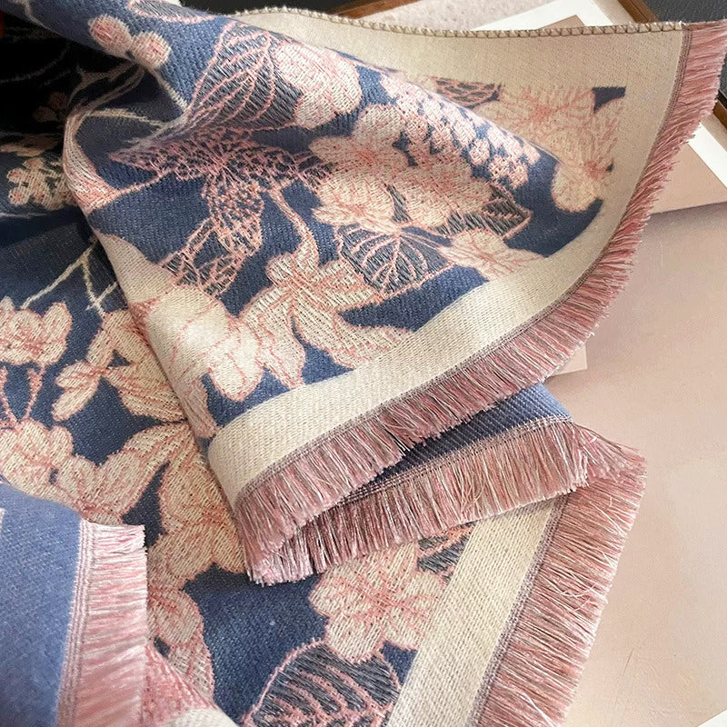 Close-up detail of cashmere-feel winter women scarf showing jacquard floral bird pattern in dusty blue and blush pink. The clear patterns feature the scarf is crafted with high-end workmanship. 