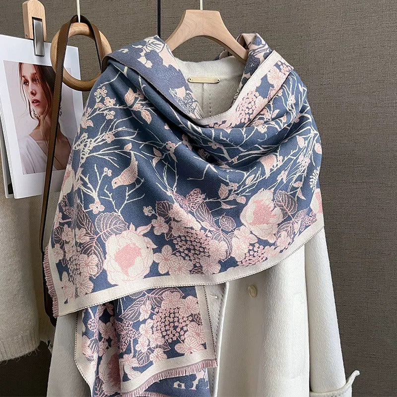 Dusty blue and blush pink jacquard scarf draped as shawl over white wool coat, showing floral birds and butterflies pattern