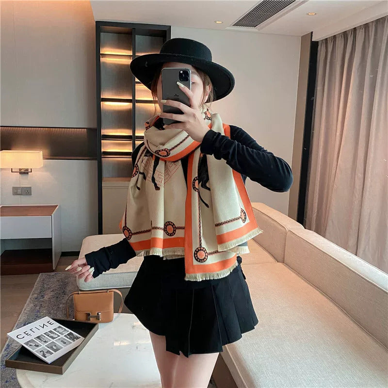 Woman wearing ivory luxury style large scarf with orange letter and border, styled as winter neck wrap