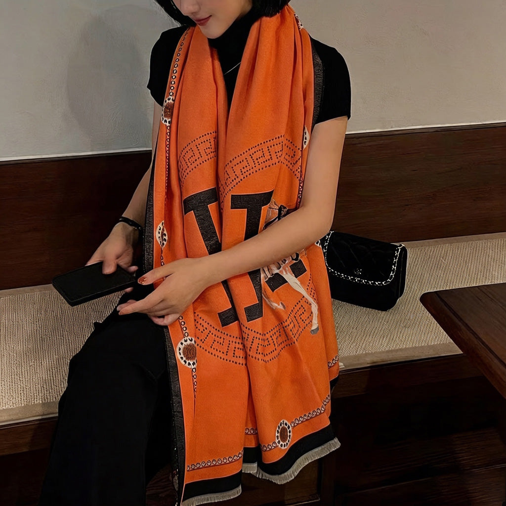 Woman wearing luxury orange equestrian print scarf with black border draped over shoulders, casual outfit