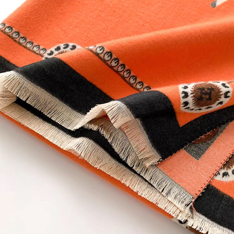 Close-up of fringed edge on orange scarf with black border and circular medallion pattern
