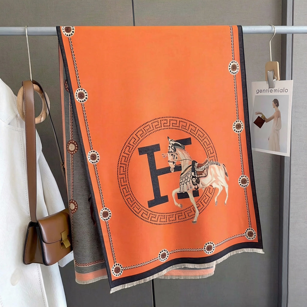 Orange luxury equestrian print scarf with black border hanging on clothing rack, horse and letter medallion design