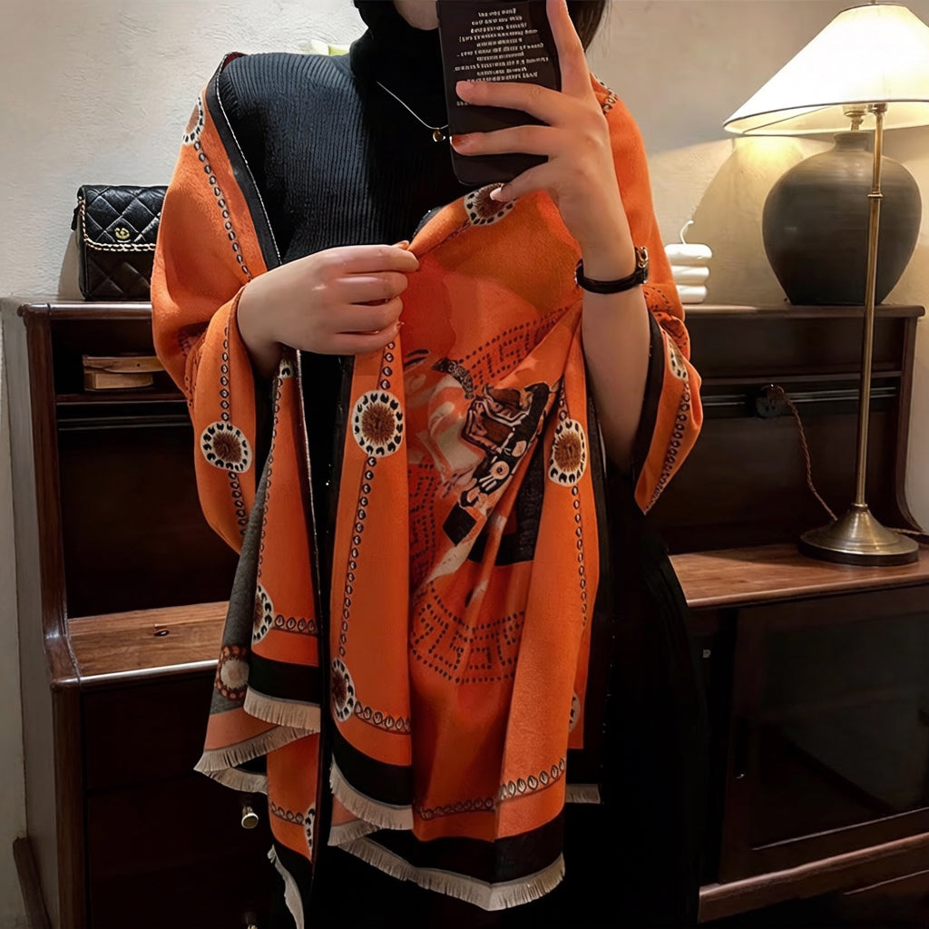 Woman wrapped in luxury orange equestrian horse print shawl with black border, cozy winter styling