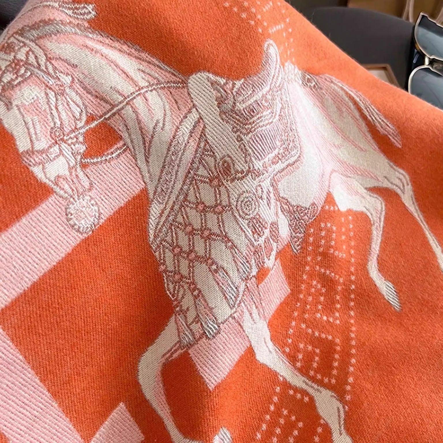 Close-up of orange large women scarf with ivory letter and border fabric. The clear horse pattern showcases the exquisite craftsmanship.