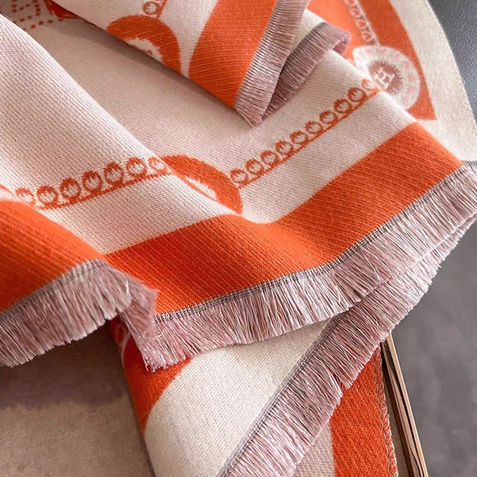 Close-up of ivory luxury equestrian print cashmere-feel winter scarf with fringe trim and orange border details