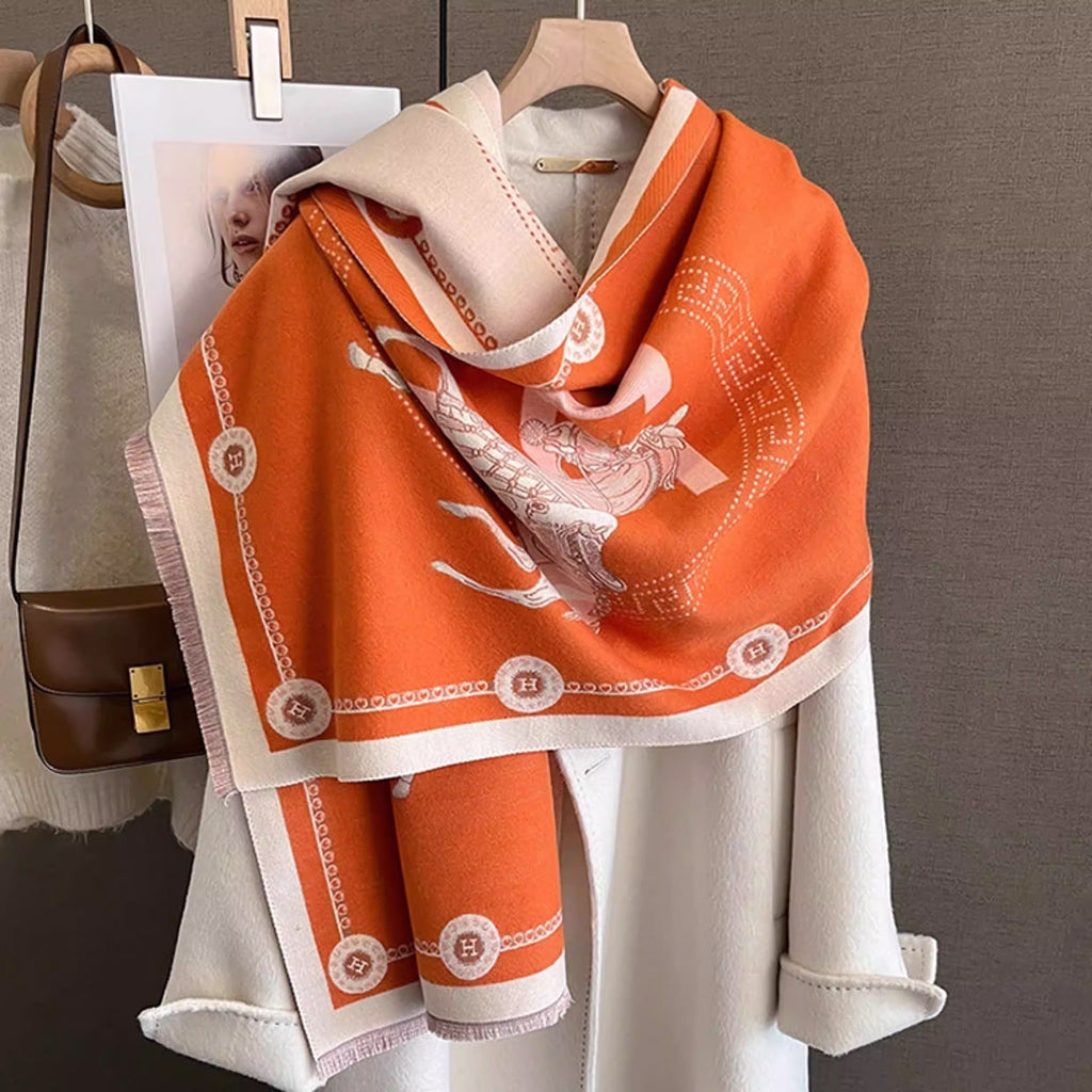 Luxuriously large jacquard scarf in orange with ivory equestrian styled over a beige coat, featuring horse print and border details.